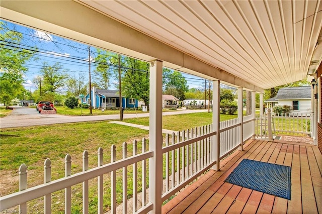 wooden deck featuring a porch and a lawn