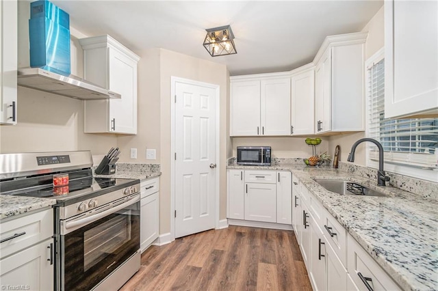 kitchen with appliances with stainless steel finishes, wall chimney range hood, dark wood-type flooring, and white cabinetry