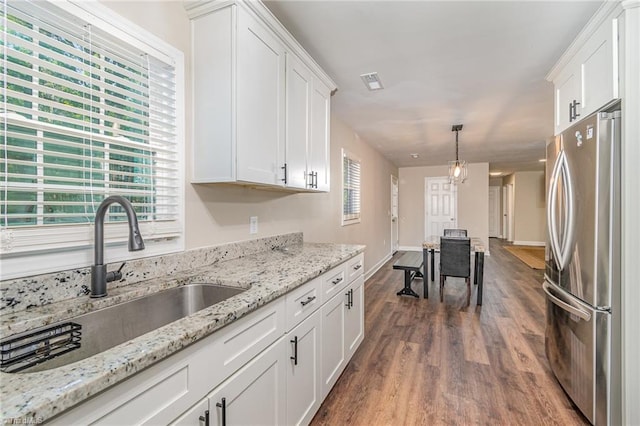 kitchen featuring dark wood-type flooring, pendant lighting, stainless steel fridge, and white cabinetry