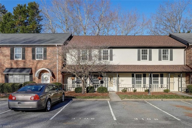 view of front of property featuring uncovered parking and a shingled roof