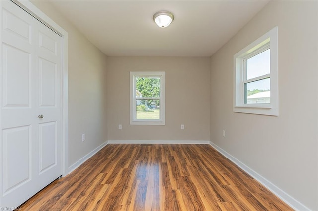 spare room with baseboards and wood finished floors