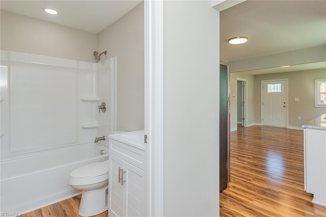 full bathroom with wood finished floors, vanity, tub / shower combination, baseboards, and toilet