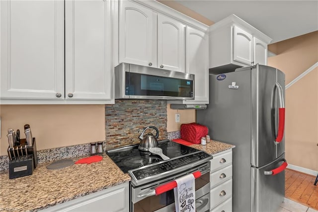 kitchen with stainless steel appliances, light stone countertops, backsplash, and white cabinets