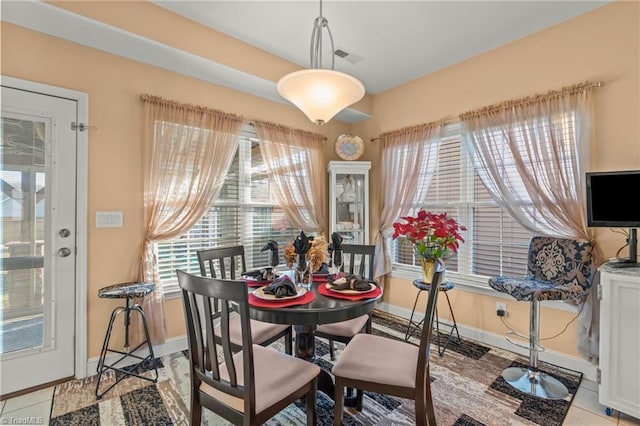 dining area featuring visible vents, light tile patterned flooring, a healthy amount of sunlight, and baseboards