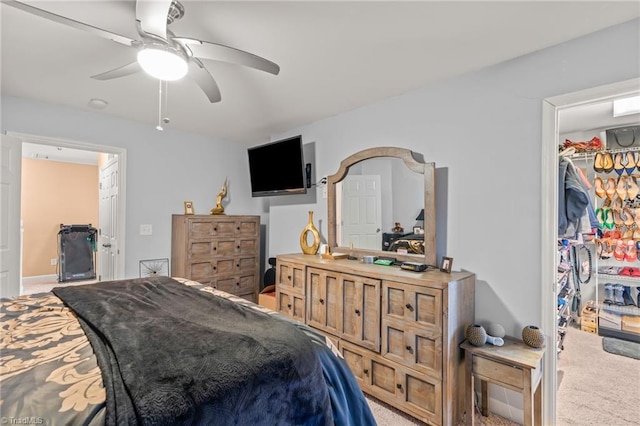 carpeted bedroom with a spacious closet, a closet, and ceiling fan