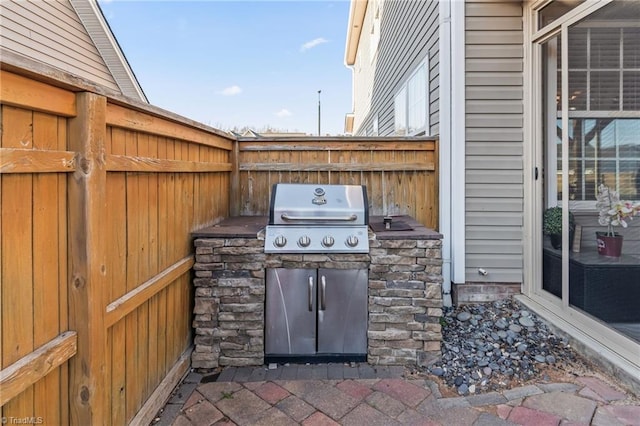 view of patio featuring a grill, exterior kitchen, and fence