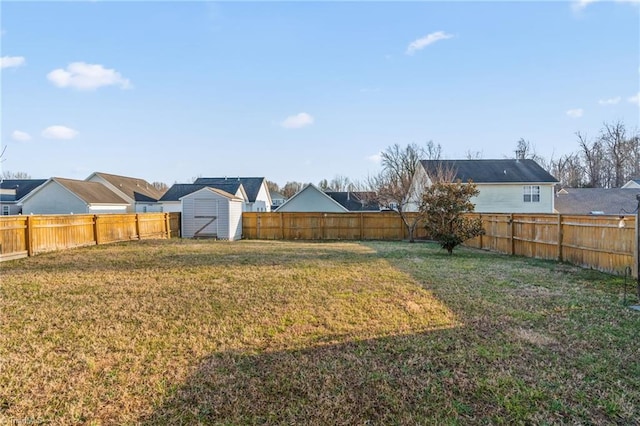 view of yard with a storage unit, a residential view, an outdoor structure, and a fenced backyard