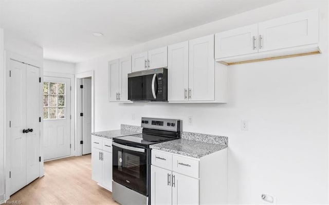 kitchen with stainless steel range with electric stovetop, light hardwood / wood-style floors, white cabinets, and light stone countertops