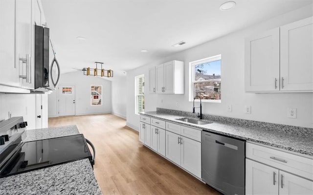 kitchen with dishwasher, sink, light stone counters, white cabinets, and range