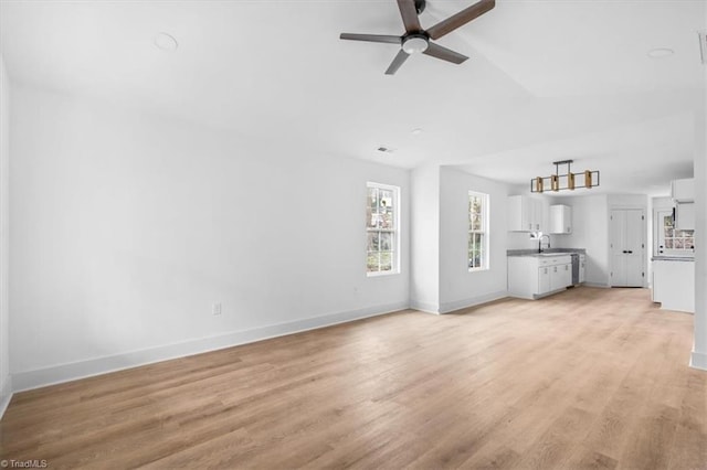 unfurnished living room with light wood-type flooring, ceiling fan, lofted ceiling, and sink