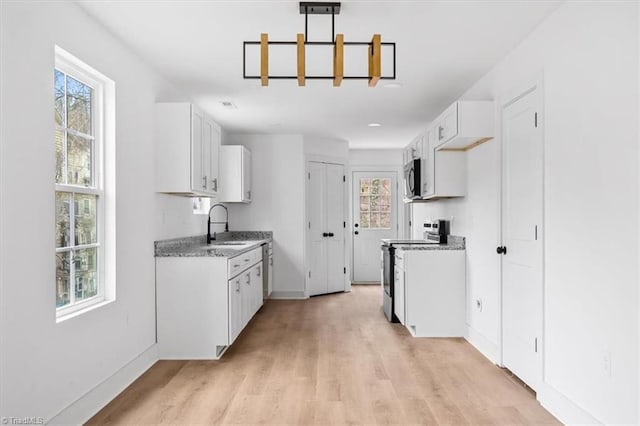 kitchen featuring sink, white cabinets, light wood-type flooring, and appliances with stainless steel finishes