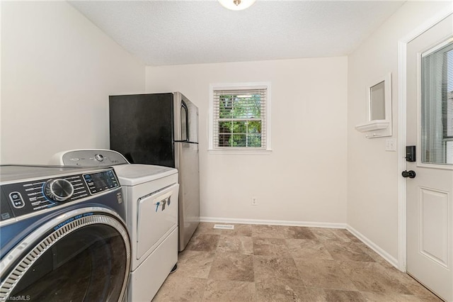 clothes washing area with a textured ceiling and washing machine and dryer