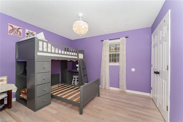 bedroom with light hardwood / wood-style flooring, a notable chandelier, and a textured ceiling