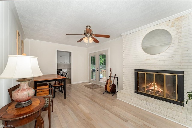 interior space with light hardwood / wood-style floors, a textured ceiling, a fireplace, crown molding, and ceiling fan