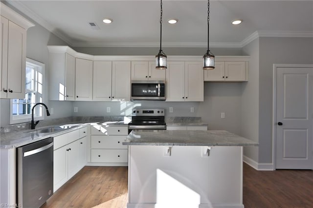 kitchen featuring appliances with stainless steel finishes, light stone counters, decorative light fixtures, a center island, and white cabinetry