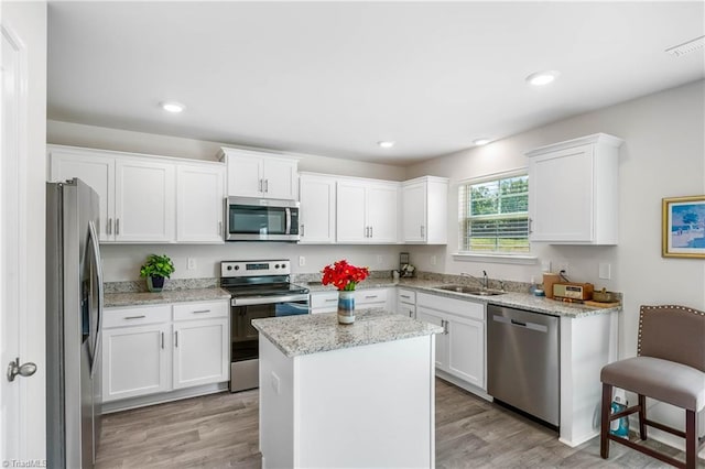141 Nova Ln, King, NC 27021 - kitchen featuring stainless steel appliances, a sink, white cabinets, a center island, and light wood finished floors
