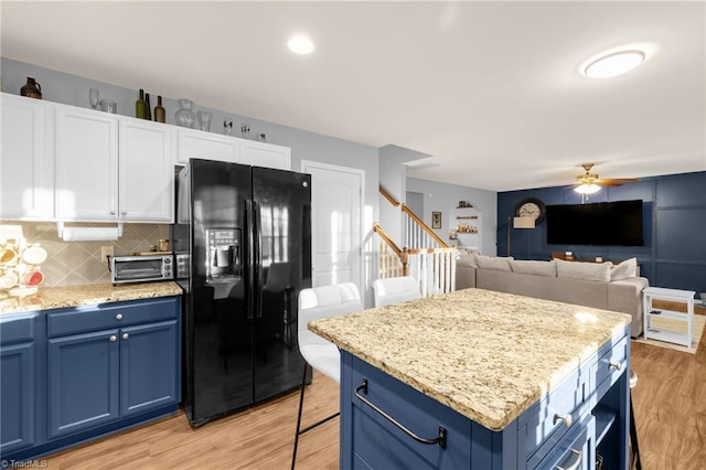 kitchen featuring white cabinets, ceiling fan, black fridge with ice dispenser, and blue cabinets