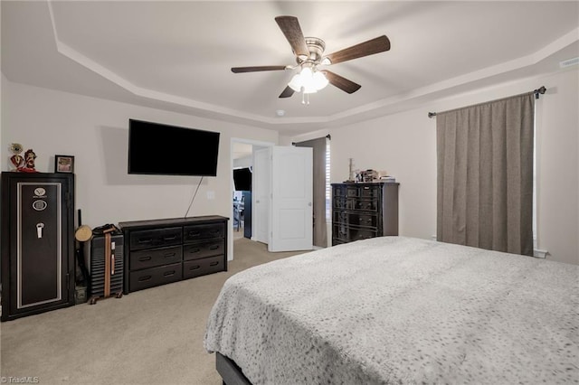 carpeted bedroom with ceiling fan and a raised ceiling