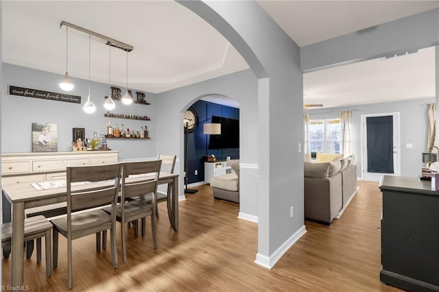 dining space featuring light hardwood / wood-style floors, bar, and track lighting