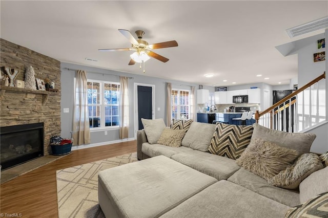 living room featuring ceiling fan, light hardwood / wood-style floors, and a fireplace