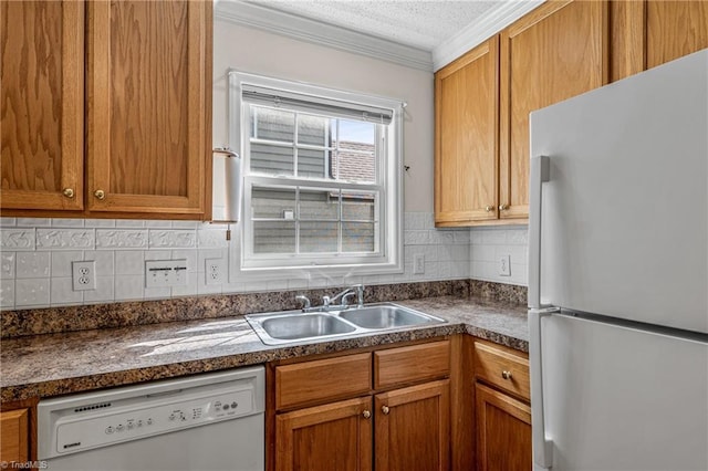 kitchen featuring dark countertops, white appliances, crown molding, and a sink