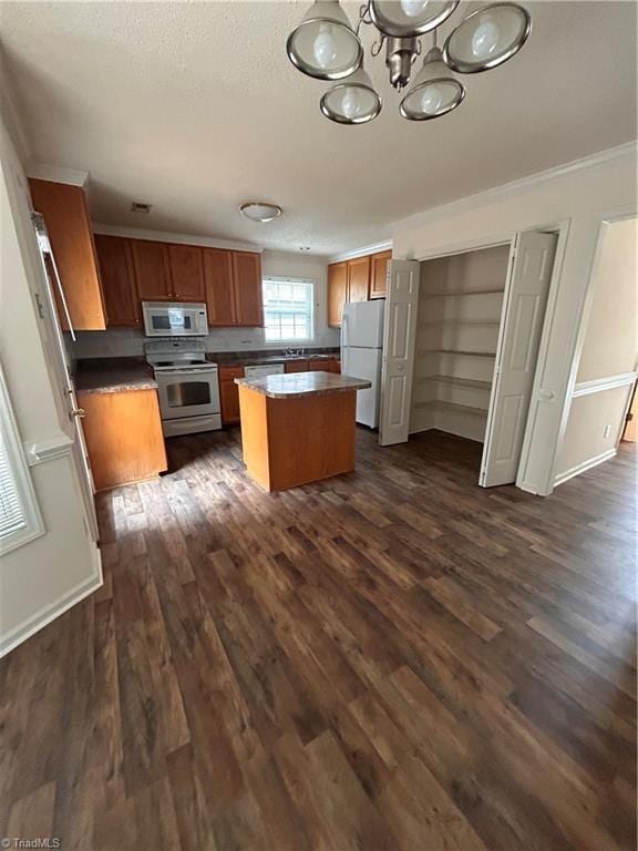 kitchen with brown cabinets, white appliances, dark wood finished floors, and a center island