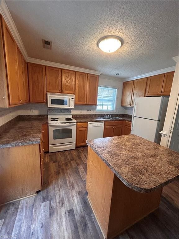 kitchen featuring white appliances, dark countertops, dark wood-style floors, brown cabinets, and a sink