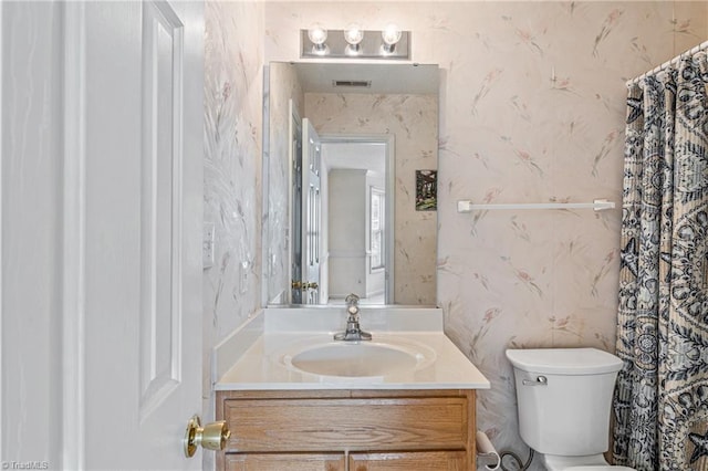 full bath featuring visible vents, vanity, toilet, and wallpapered walls