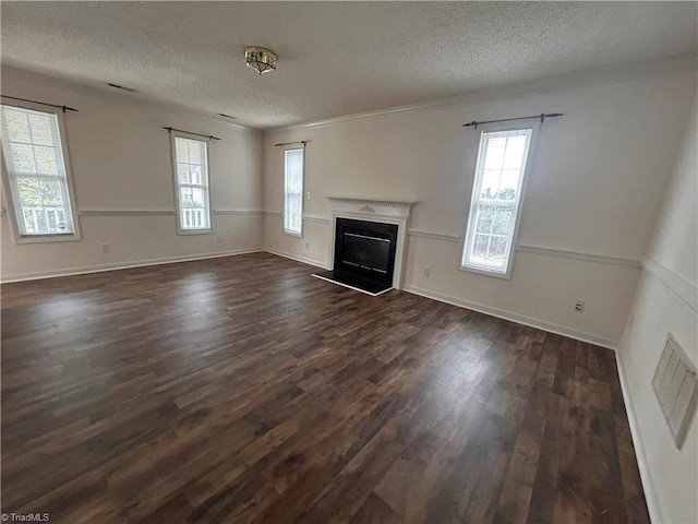 unfurnished living room with baseboards, dark wood finished floors, a textured ceiling, and a glass covered fireplace