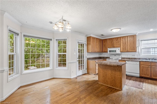 kitchen with white appliances, decorative backsplash, dark countertops, light wood-style flooring, and crown molding