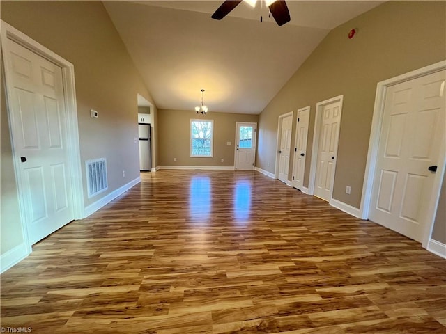 spare room with high vaulted ceiling, visible vents, baseboards, and wood finished floors