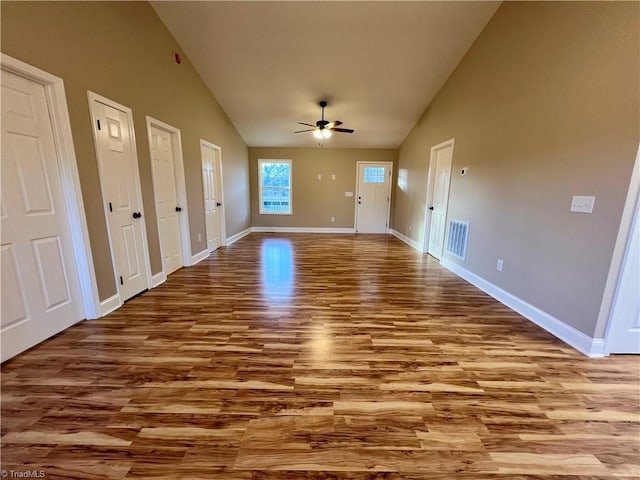 interior space with ceiling fan, high vaulted ceiling, light wood-style flooring, visible vents, and baseboards