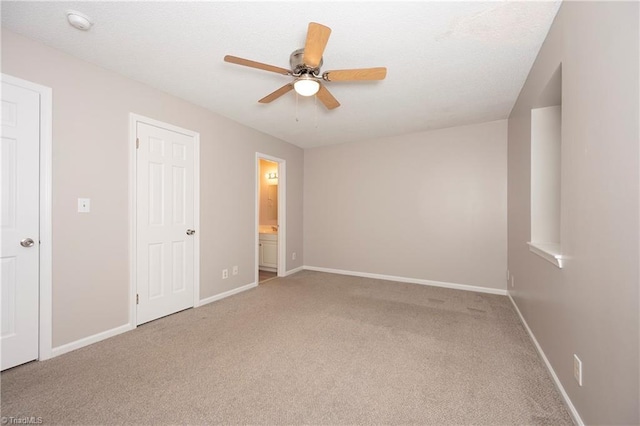 unfurnished bedroom with carpet flooring, ceiling fan, and ensuite bath