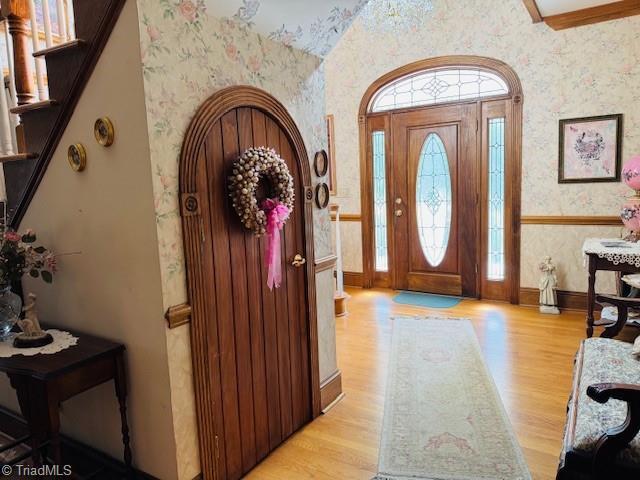526 Bob Rainey Trl, Burlington, NC 27217 - foyer entrance with wallpapered walls, light wood finished floors, baseboards, vaulted ceiling, and stairway