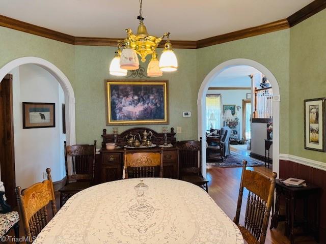 526 Bob Rainey Trl, Burlington, NC 27217 - dining space with arched walkways, a chandelier, wood finished floors, and ornamental molding