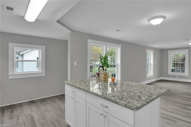 kitchen with white cabinetry, plenty of natural light, light wood-type flooring, and light stone counters