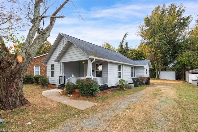 view of front of house featuring a front lawn, a storage shed, and covered porch