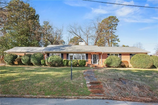 single story home with a front yard, brick siding, and a chimney