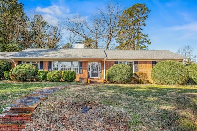 ranch-style house with a front yard, brick siding, and a chimney