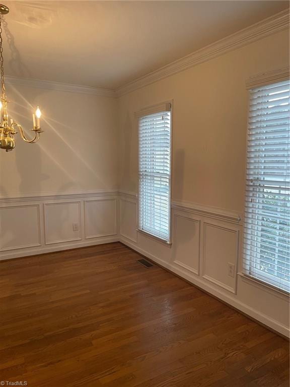 empty room featuring ornamental molding, dark hardwood / wood-style floors, and a chandelier