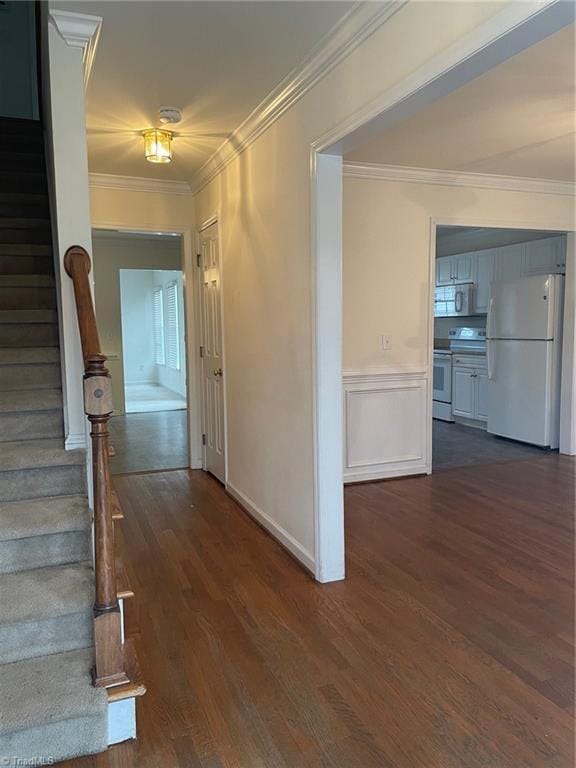 hall with dark wood-type flooring and ornamental molding