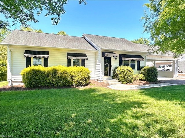 ranch-style home with concrete driveway, a shingled roof, a front lawn, and an attached garage