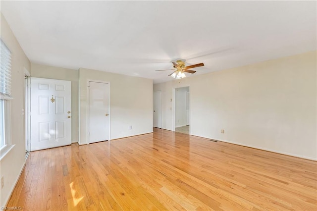 unfurnished room featuring light wood finished floors, baseboards, a ceiling fan, and visible vents