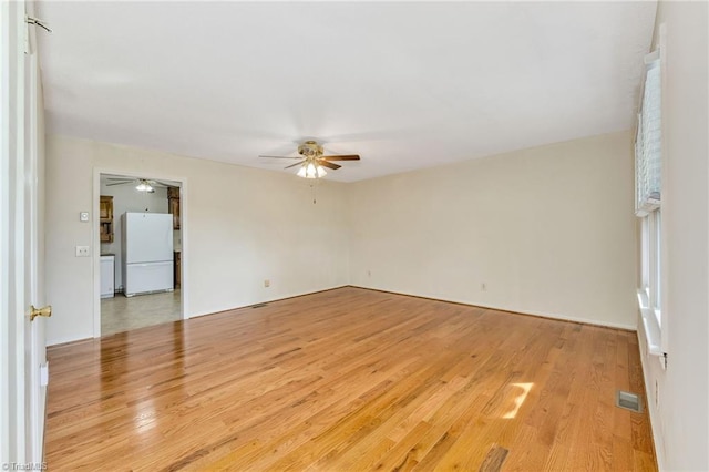 unfurnished room featuring visible vents, light wood-style flooring, and ceiling fan