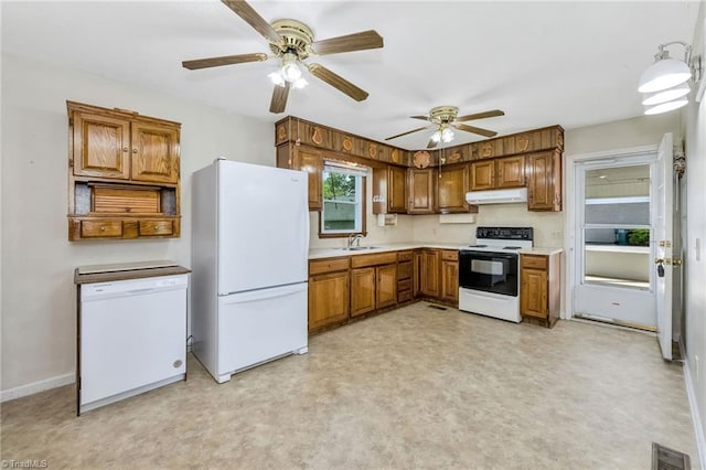 kitchen featuring a sink, brown cabinetry, white appliances, under cabinet range hood, and light countertops
