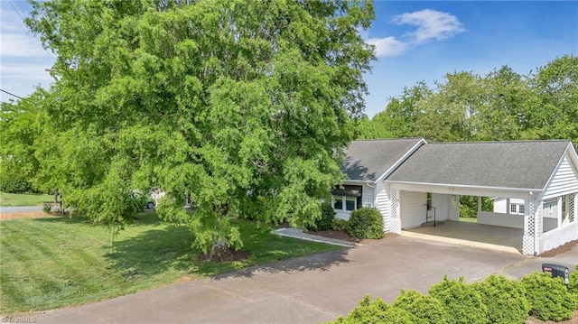 view of front of property with a front lawn, driveway, roof with shingles, and a carport