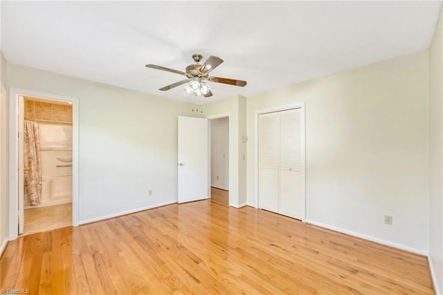 unfurnished bedroom with connected bathroom, a closet, light wood-type flooring, and baseboards