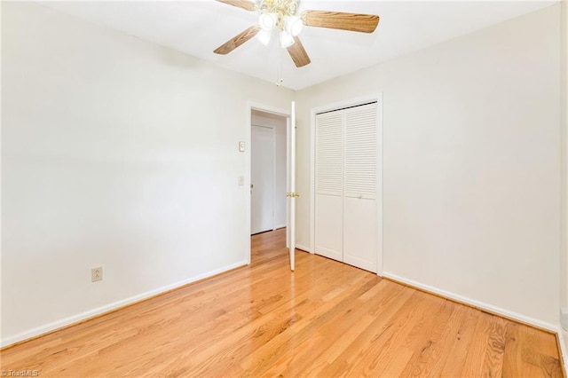 unfurnished bedroom featuring a closet, wood finished floors, baseboards, and ceiling fan