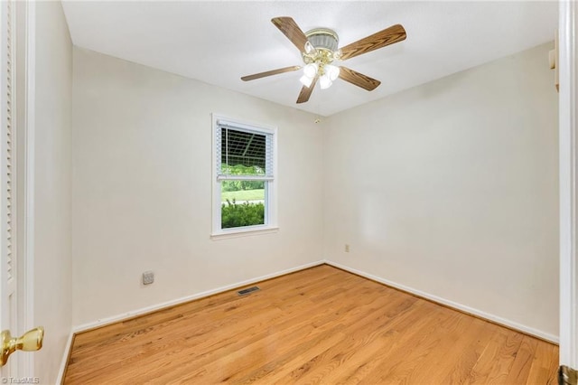 spare room featuring a ceiling fan, visible vents, wood finished floors, and baseboards