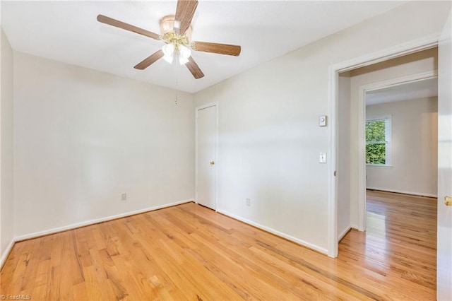 spare room featuring baseboards, light wood-style flooring, and a ceiling fan